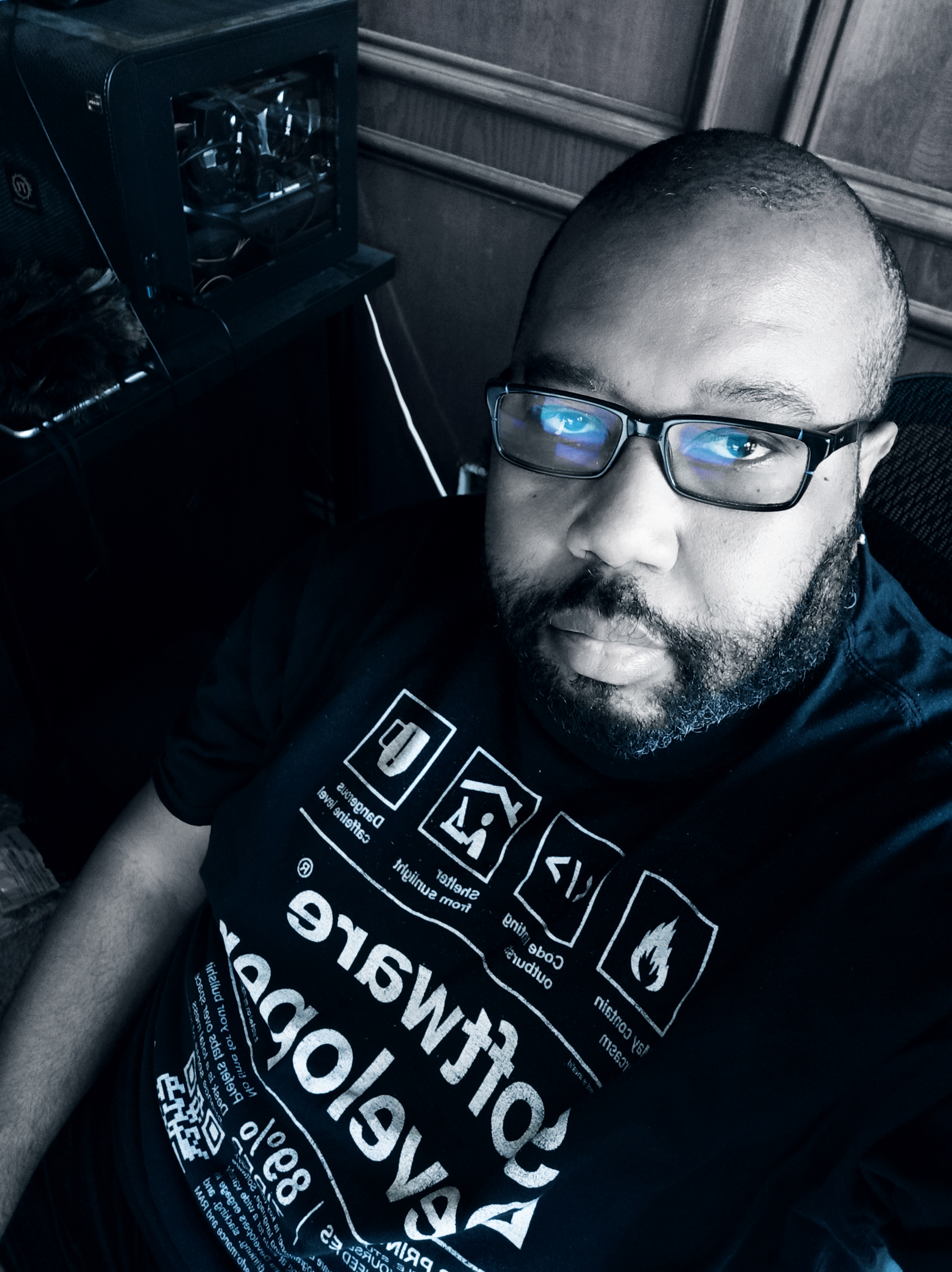 A smiling man poses near a tree